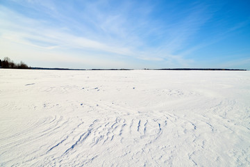 Fototapeta na wymiar Winter landscape with snow covered field and blue sky with clouds