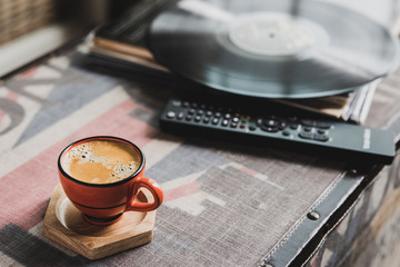 cup of coffee espresso  with vinyl record and remote tv on the table