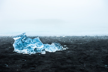 Blue ice on the Jokulsarlon ice beach at foggy day, southern Iceland.