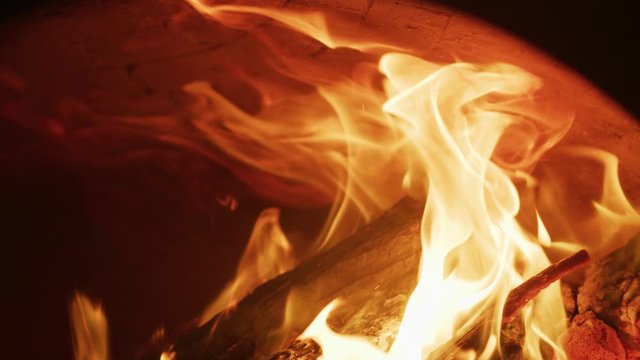 Wood fire burns in a pizza oven in slow motion.
