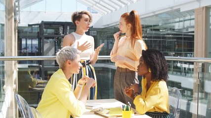 Young Afro female designer giving new ideas about project to his partner in conference room. Business people discussing project in the background of the office.