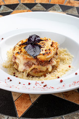 Traditional lasagna made with minced beef bolognese sauce topped with coriander leafs served on a white plate