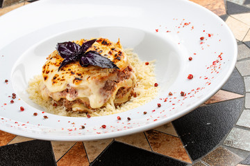 Traditional lasagna made with minced beef bolognese sauce topped with coriander leafs served on a white plate