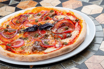 Pizza with veal tenderloin, pepper and sweet onion rings. On the stone table