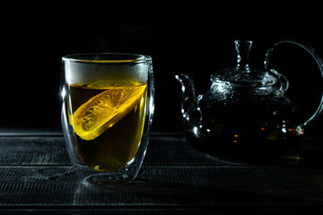 hot fresh black tea with lemons in transparent thermocup. Glass teapot. Tea ceremony