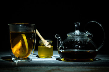 hot fresh black tea with slice lemon in transparent thermomug and honey. Glass teapot. Tea ceremony