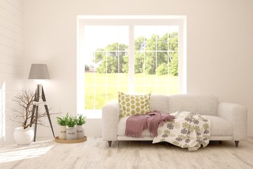 Fototapeta premium Stylish room in white color with sofa and summer landscape in window. Scandinavian interior design. 3D illustration