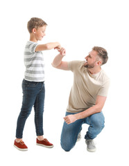 Portrait of happy father and son bumping fists on white background