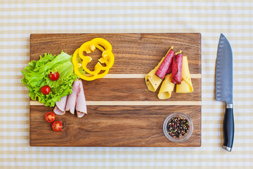 Healthy food delivery background. Cutting board with a knife, pepper, tomatoes, spices, lettuce, cheese.