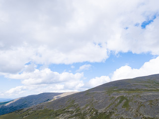 Fototapeta premium landscape of the ridge covered with green trees and view a valley flooded with sunlight ,pasture, with dense clouds in the sky. summer day in the mountains of the Altai