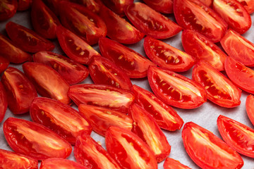Homemade dried red  tomatoes slices with basil oregano spices cooking process. Traditional Italian Mediterranean kitchen cuisine.