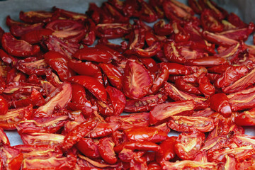 Homemade dried red  tomatoes slices with basil oregano spices cooking process. Traditional Italian Mediterranean kitchen cuisine.