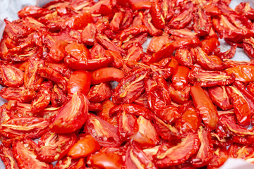 Homemade dried red  tomatoes slices with basil oregano spices cooking process. Traditional Italian Mediterranean kitchen cuisine.