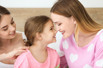 Happy lesbian couple with little daughter in bedroom