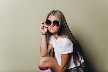 Close up portrait of young girl with long hair in sun glasses posing in studio