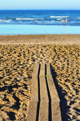A sandy beach in summer daytime withe blue sea in the background. Travel and summer vacation concept with peace and tranquility.