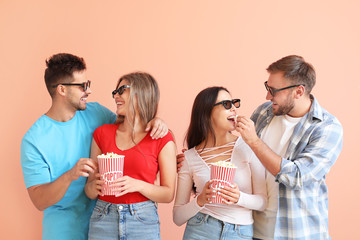 Friends eating popcorn on color background