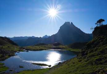 Ayous lakes with Mount Midi d'Ossau and the sun in the background in the Natural Park of the Pyrenees, France