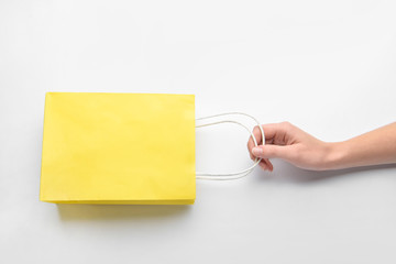 Female hand with shopping bag on white background