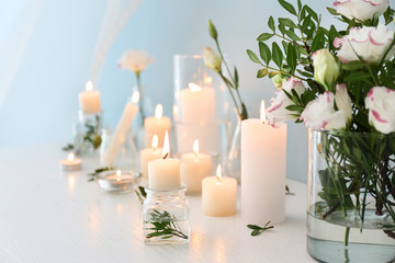 Beautiful burning candles and flowers on table