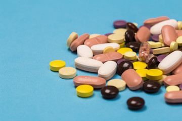 many scattered Colorful medical pills on pastel blue background
