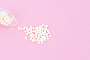 Homeopathy eco medicine concept - classical homeopathy pills in vintage glass bottles on pink background. Flatlay. Top view. Copyspace