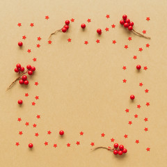 Christmas Flame made from red berries and star on paper background. Flat lay, top view.