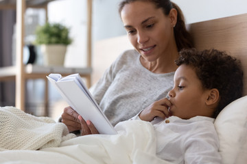 Mom and little kid son read book in bed