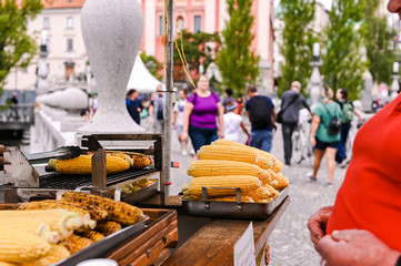 Grilled corn. Fast food in the city center for tourists. Selling food on the street. Hands in the frame of the buyer and seller.