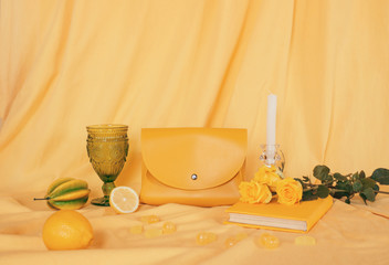 yellow objects: bag, book, lemon, candy, flowers on a yellow background. fabric background, layout, place for text. design