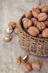 Walnuts in a round wicker basket on a wooden background. Place for your text