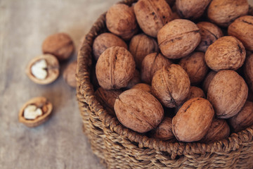 Walnuts in a round wicker basket on a wooden background. Place for your text