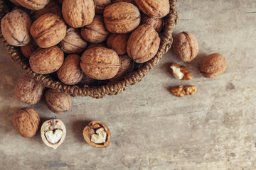 Walnuts in a round wicker basket on a wooden background. Top view. Copy, empty space for text