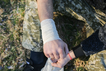 Man is putting bandage on sprained wrist. Twisted arm. Injured tourist in the nature. Hiking.