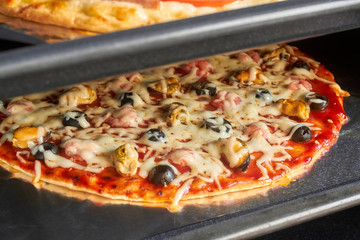 Delicious homemade pizza with seafood in hot air oven. Cooking homemade pizza with shrimp, mussels,...