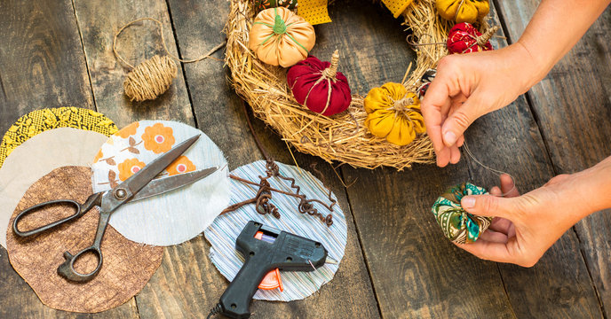 Decorating a straw wreath handmade textile pumpkins. Hands make textile pumpkin. Preparing for the harvest festival. DIY