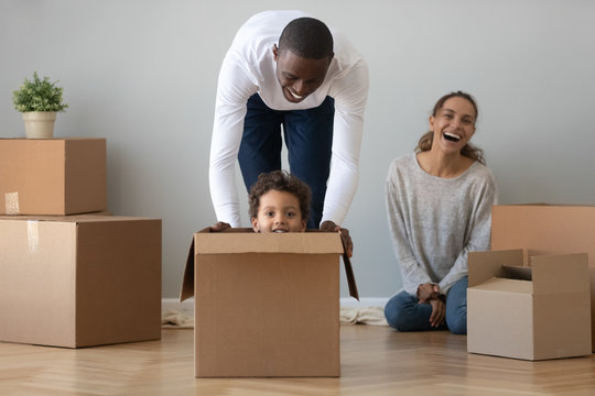 Black dad playing riding son in box on moving day