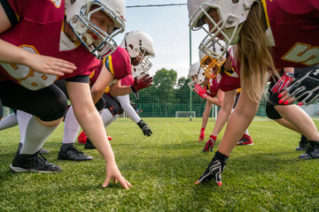 Photo of athletes women wearing helmets playing american football on green lawn