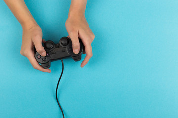 Female hands hold a gamepad on a blue background. Weekend concept, gaming hobby. Copy space.