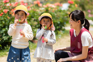 Obraz premium 公園で遊ぶ保育士と園児たち