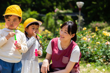 Obraz premium 公園で遊ぶ保育士と園児たち