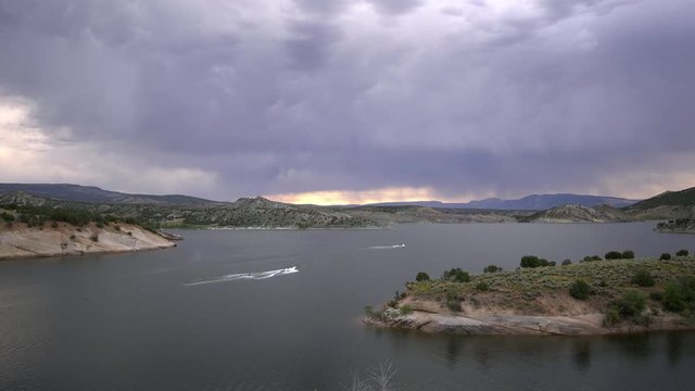 2 boats pulling people on Red Fleet Reservoir as they play on the water with storm clouds overhead.