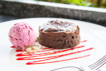 Warm dessert chocolate cake Fondant on plate with ice-cream ball, mint, icing on the table in a summer cafe under an open sky. Chocolate lava cake with ice cream