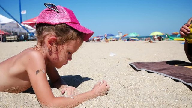 Little girl sunbathes in the sand on the beach