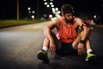 Male runner resting after night workout in the city.