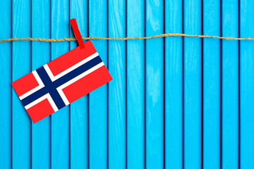 Flag of Bouvet Islands hanging on clothesline attached with wooden clothespins on aqua blue wooden background. National day concept.