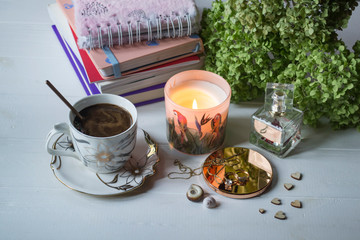 A cup of coffee with female accessories and hydrangea flower on a table, top view.