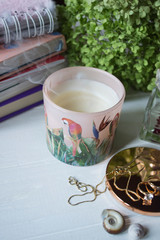 Put out candle with smoke. Home decor and female accessories on a table, close up.