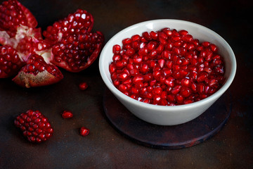 Pomegranate seeds in a bowl on black background.