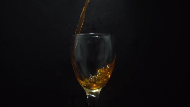 Pouring Fresh Orange juice in wmpty glass isolated on black background